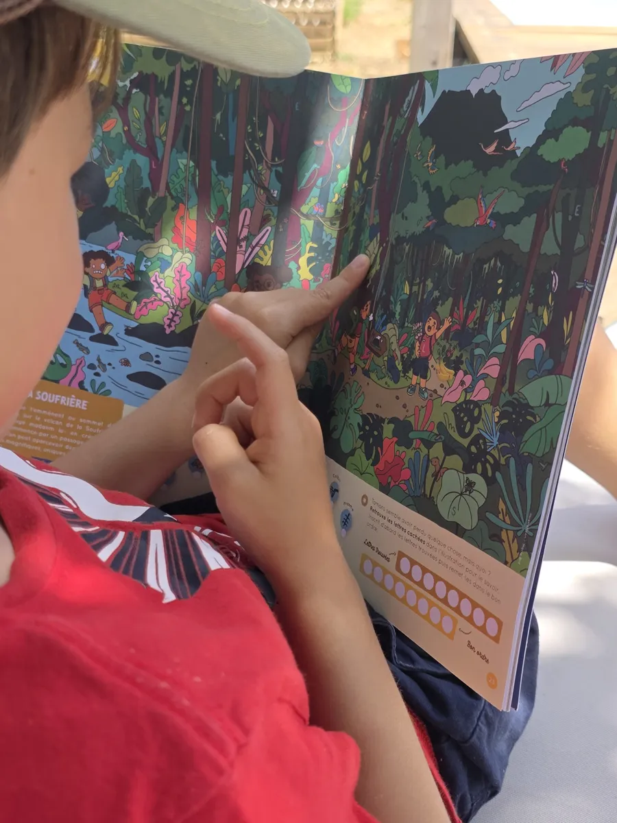 Enfant cherchant les lettres cachées dans une illustration de forêt tropicale du magazine Petit Péyi