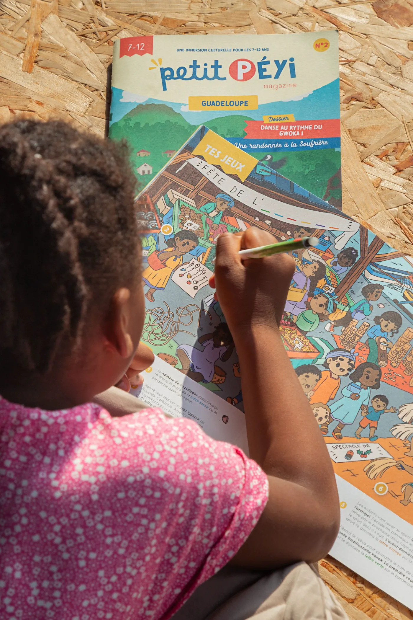 Enfant coloriant une page du magazine Petit Péyi