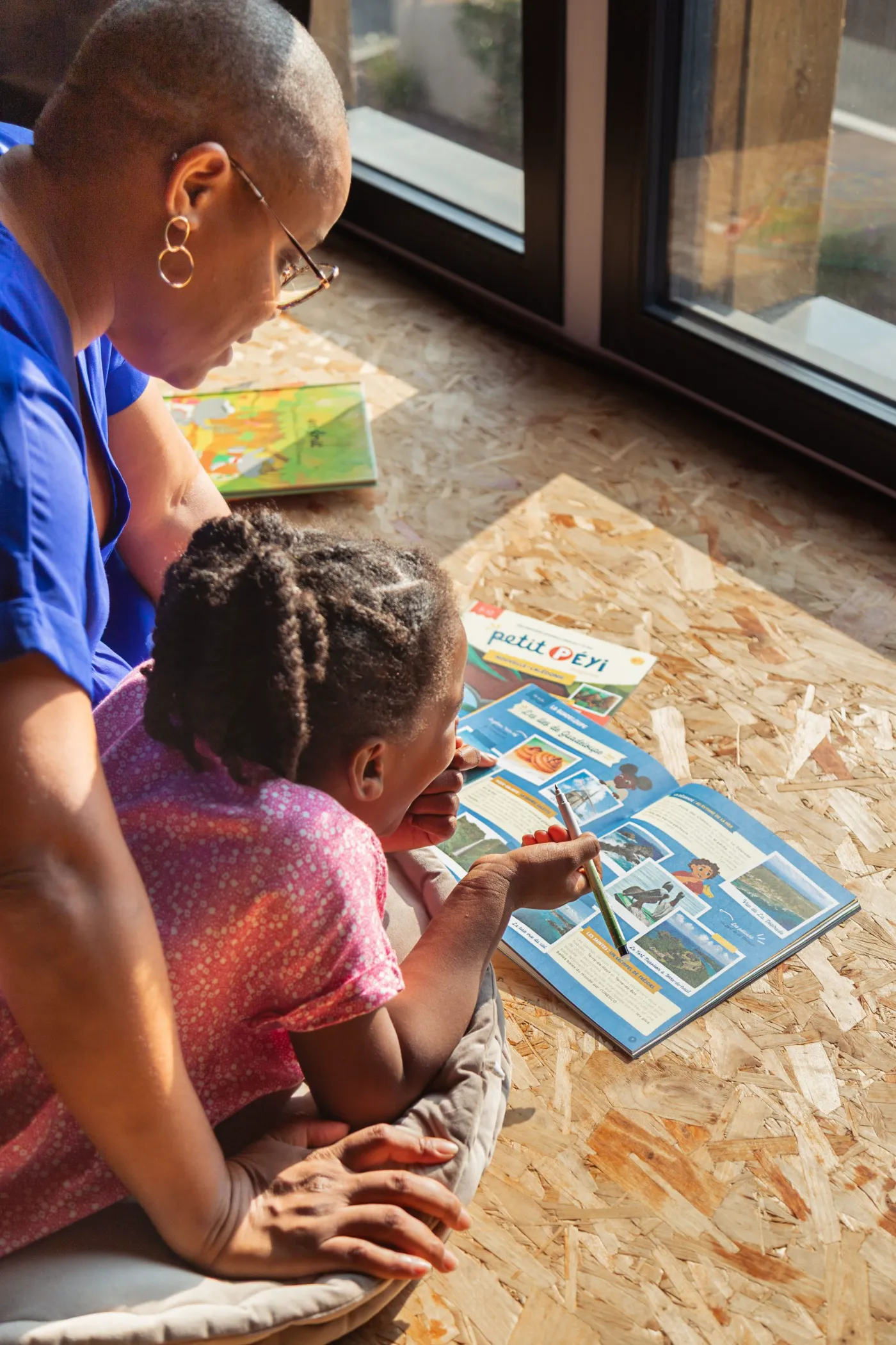 Maman et sa fille lisant ensemble le magazine Petit Péyi